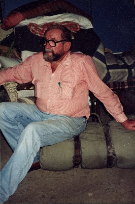 Bud Ford sitting on swag containing rolled lamb skin rug